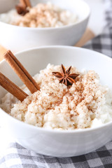 Bowl with delicious rice pudding and cinnamon powder on table, closeup