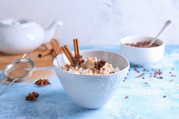 Bowl with delicious rice pudding and cinnamon powder on light table