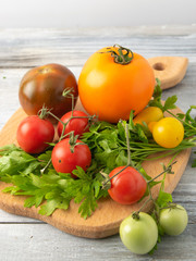 Homemade tomatoes from the meadow to the table are natural mixes of different colors and sizes. Presented on a board and a spoon.