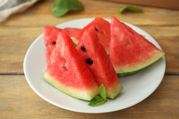 Plate with sweet watermelon slices on wooden table