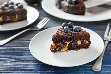 Plate with piece of blueberry chocolate cake on wooden table