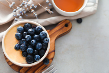 Bowl with delicious blueberry pudding on light table