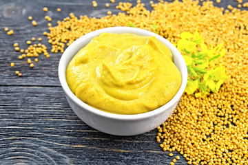 Sauce mustard in bowl with flower on board