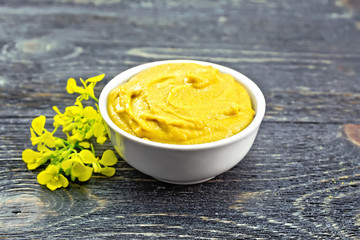 Sauce mustard in bowl with flower on dark board