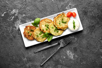 Plate with zucchini pancakes and sauce on grunge table