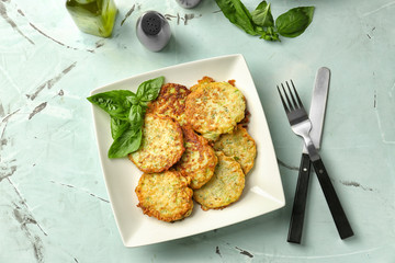 Plate with zucchini pancakes on table