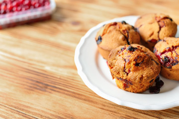 Plate with tasty muffins on wooden table, closeup