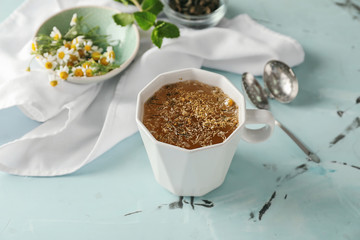 Cup of delicious camomile tea on light table