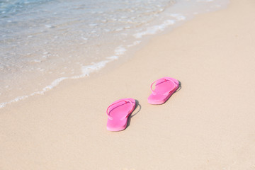 Fototapeta na wymiar Bright flip-flops on sea beach