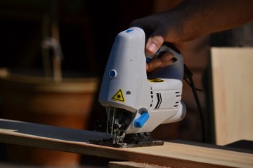 Cutting the boards with a jigsaw - the chips are flying (close-up)