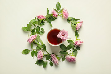 Beautiful rose flowers with cup of tea on white background, top view