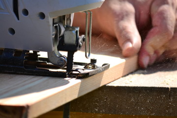 Cutting the boards with a jigsaw - the chips are flying (close-up)