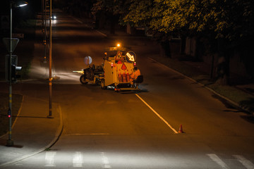 Thermoplastic spray marking machine during road construction works at night. Traffic line painting...