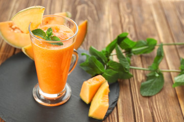 Glass of fresh melon smoothie on wooden table