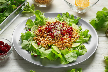 Plate with healthy fresh salad on white wooden table