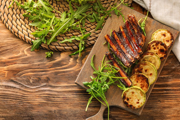 Delicious grilled ribs with arugula and zucchini on wooden table