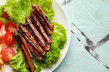 Delicious grilled ribs with vegetables on plate