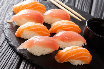 Tasty dietary sushi with salmon and tuna, soy sauce close-up on a black slate. horizontal