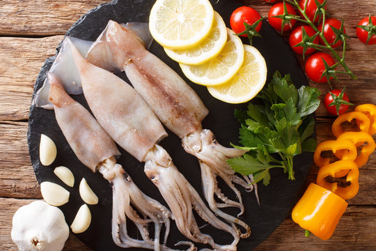 Seafood fresh squid with tentacles close-up and vegetable on the table. horizontal top view from above