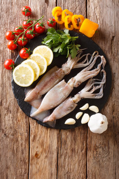 Fresh raw squid with tentacles closeup and vegetable ingredients. Vertical top view from above