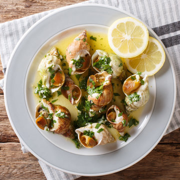 French recipe Whelks with a sauce of butter, garlic and parsley, lemon close-up. top view from above