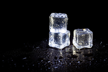 ice cubes reflection on black table background.