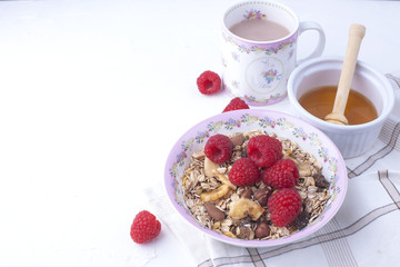 Delicious and healthy breakfast on a white background. Porridge of oatmeal, raspberry, honey, coffee for a good morning. Free space for text, top view