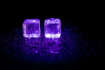 Purple ice cubes reflection on black table background.