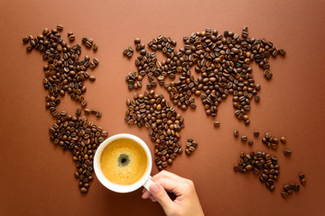 Map of the world made of roasted coffee beans on brown paper background. International coffee industry or travel planning concept