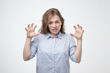 Caucasian woman showing her wild side posing in blue shirt growling at you and gesturing a claw...
