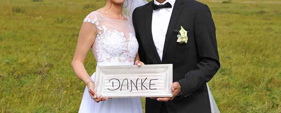 ehepaar brautpaar h&auml;lt schild zeichen mit danke danksagung und bedankt sich symbolisch bei den g&auml;sten