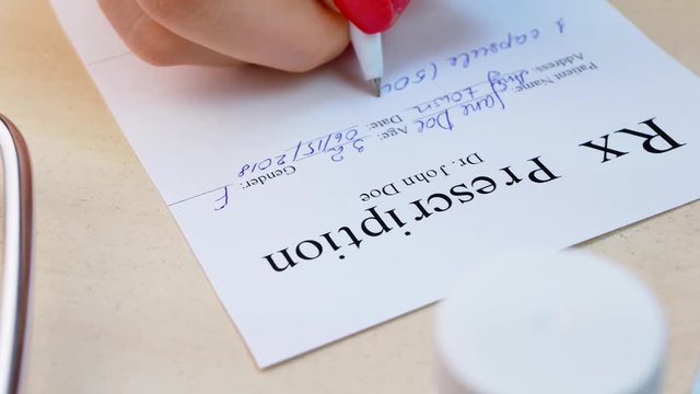 Doctor hand writing rx prescription list to patient. Concept of healthcare and medically