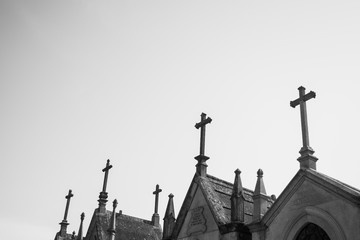 Crosses on top of old graves, with a clear sky in the background.