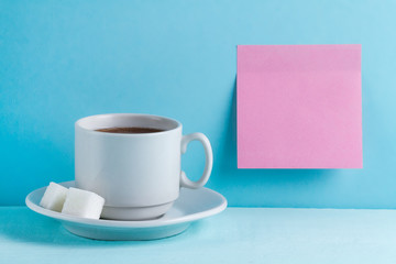 A cup of hot coffee on a blue background. The beginning of the day, awakening. Cheerfulness. Sticker, reminder, message, note. Copy space