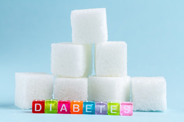 Pieces of sugar and inscription diabetes mellitus on a blue background. Diabetes.