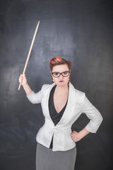 Angry teacher with pointer on the chalkboard background