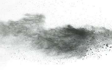 Black powder explosion. Closeup of black dust particles explode isolated on white background.