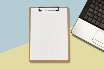Clipboard with white sheet and laptop on pastel color background