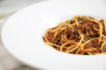 spaghetti Bolognese with minced beef and tomato sauce garnished with parmesan cheese and basil , Italian food
