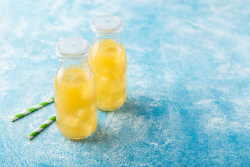 Fresh pineapple juice and ripe pineapple on grey background