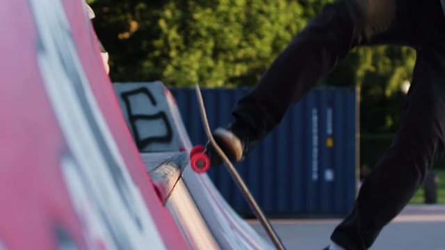 Skateboarder riding halfpipe ramp closeup. Slow motion