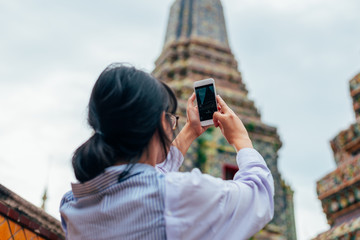 Asian woman solo travelers use smartphone take photo ancient pagoda buildings- Wat pho temple-...