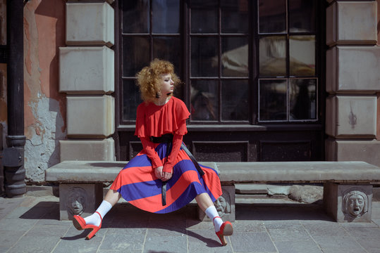 Young woman with curly hair in red retro dress. Walk around the city