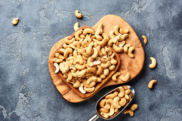 Roasted cashew nuts and scoop on gray background. Top view.