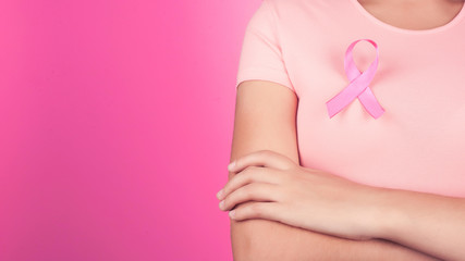 healthcare, people, charity and medicine concept - close up of woman in t-shirt with breast cancer awareness ribbon over pink background.