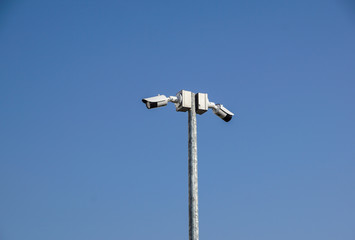CCTV surveillance security camera on a black pole with blue sky background