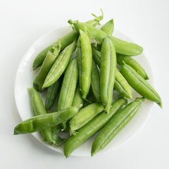 Pea pods on a plate on a white background.