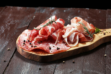 Food tray with delicious salami, ham,  fresh sausages and herbs. Meat platter with selection