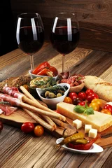 Tragetasche Italian antipasti wine snacks set. Cheese variety, Mediterranean olives, crudo, Prosciutto di Parma, salami and wine in glasses over wooden grunge background. © beats_
