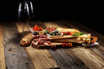 Fotobehang Italian antipasti wine snacks set. Cheese variety, Mediterranean olives, crudo, Prosciutto di Parma, salami and wine in glasses over wooden grunge background. © beats_